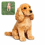 A golden-colored dog with long ears sits attentively on a lush green grassy field, looking off to the side as if pondering the mysteries of the park.