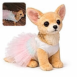 A tiny dog dressed in a delicate pastel tutu stands on a wooden floor, looking up with big, expressive eyes as if ready for a dance recital or a fancy party.