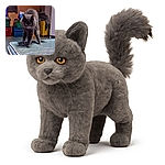 A fluffy gray cat with piercing yellow eyes is cautiously stepping on a worn mattress in a cluttered room filled with colorful storage bins and a bright yellow suitcase. The cat's tail is fluffed up, giving it a curious yet slightly startled appearance.
