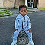 Isaac a rejoint le concours — aidez-le/la à gagner de superbes lots ! child, toddler, tracksuit, grey_clothing, sneakers, concrete_bollard, urban, pavement, brick_building, door, outdoor, serious_expression, person, street, sidewalk, grass, stick, fashion, casual, young_child