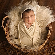 Izza participe au concours pour gagner de l'argent avec cette photo : baby, infant, swaddled, basket, knit_hat, bear_ears, sleeping, cozy, fluffy, blanket, wooden_floor, cute, newborn, peaceful, portrait, soft_textures, indoors, resting, child, adorable