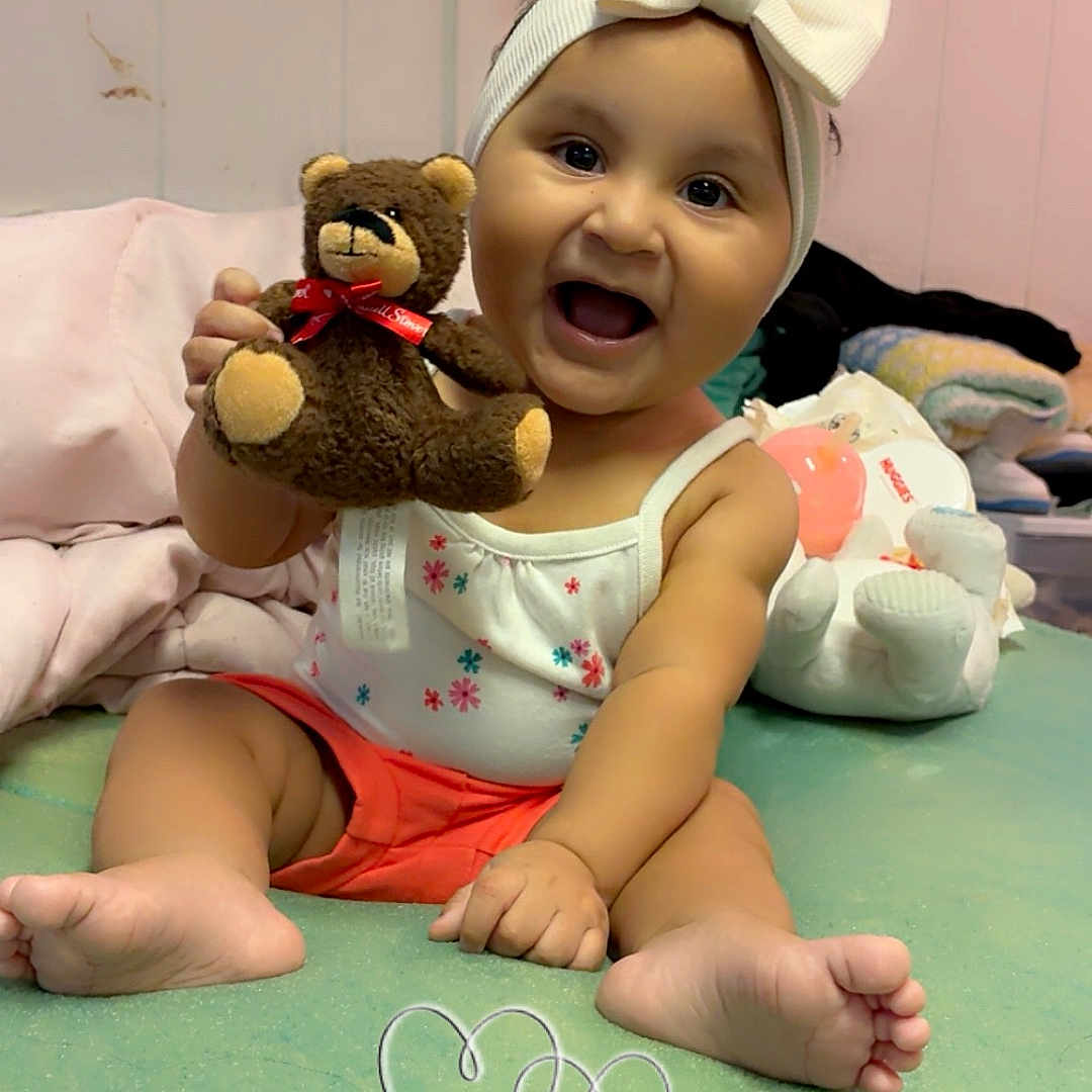 Valentina joined the competition — help win amazing prizes! baby, blanket, bow, child, clothing, cozy, cute, face, feet, happy, headband, indoors, infant, person, playful, room, sitting, smile, teddy_bear, toy