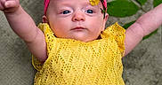 Willow is registered to the contest to win money with this photo: baby, child, infant, yellow_dress, pink_headband, flower, leaf, arms_up, cute, portrait, laying_down, outdoor, nature, soft_texture, daisy, headwear, smiling_face, human, closeup, toddler