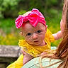 Willow is registered to the contest to win money with this photo: baby, child, pink_bow, yellow_dress, lace, person, holding, green_background, outdoor, portrait, headwear, curious, infant, close_up, face, young_child, human, nature, summer, cute