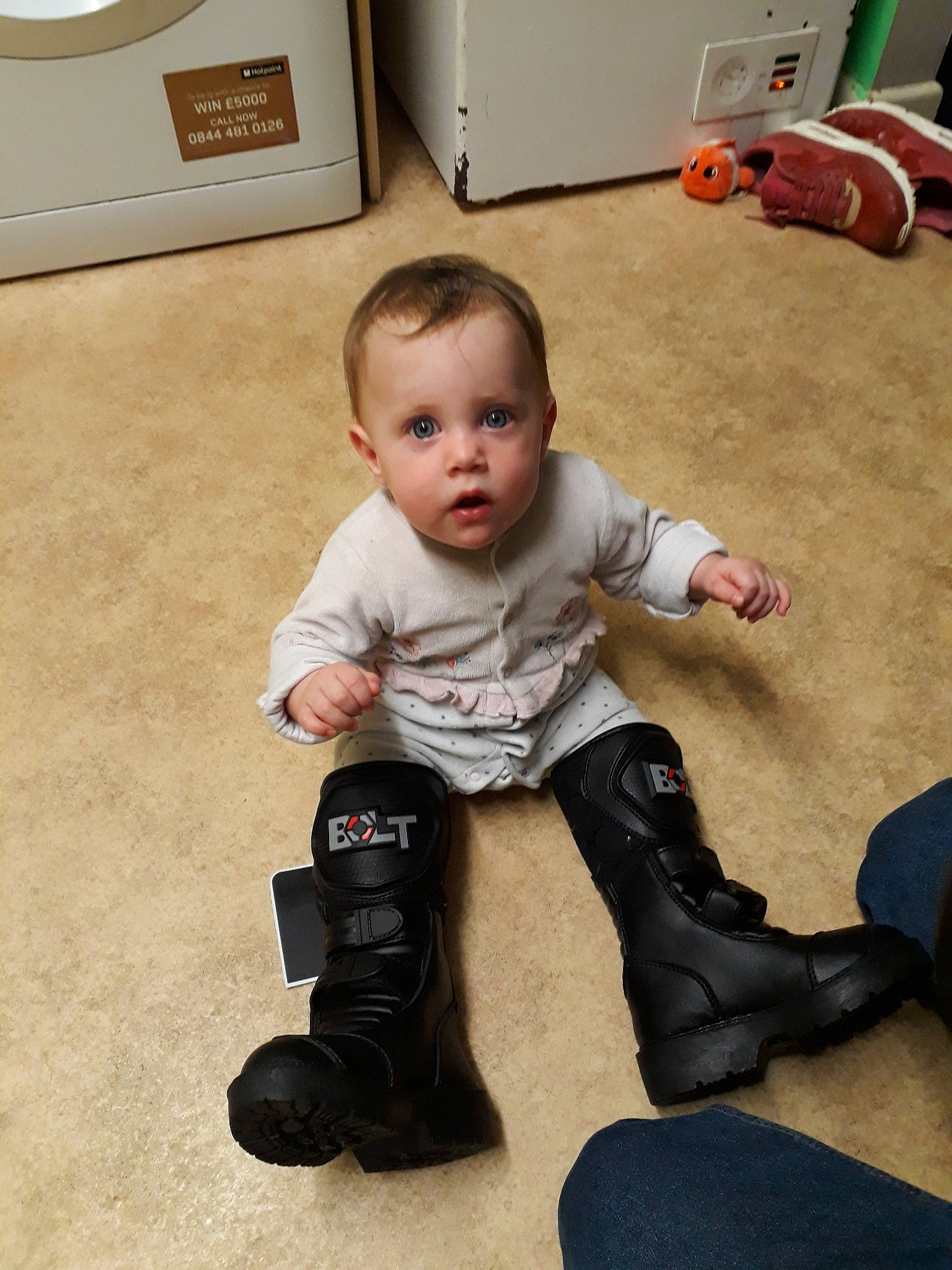 Rosie-grace is registered to the contest to win money with this photo: ankle, baby, child, floor, flooring, footwear, joint, leg, person, shoe, sitting, surprise, toddler