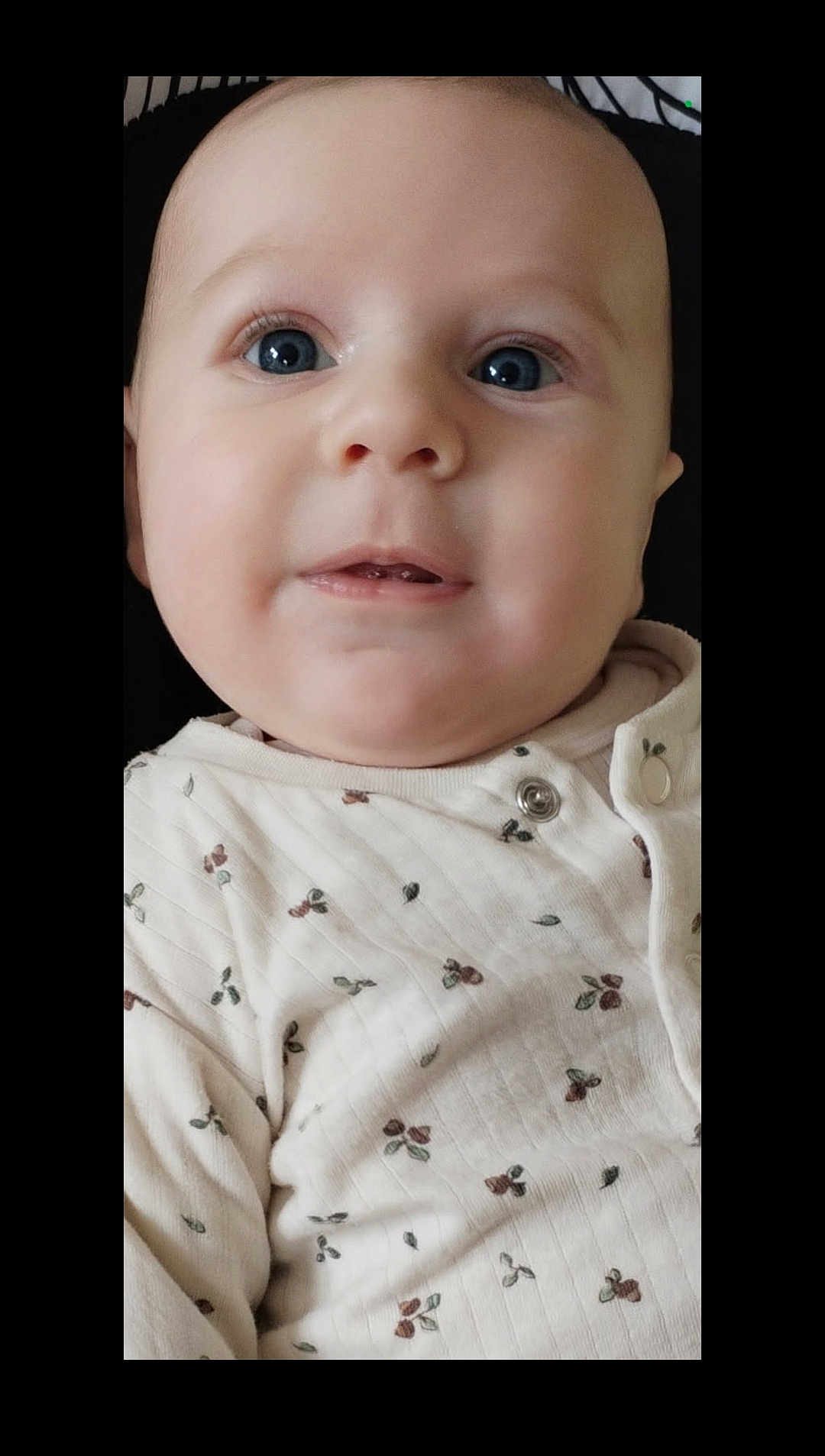 Adam participe au concours pour gagner de l'argent avec cette photo : baby, infant, face, blue_eyes, cute, clothing, white_outfit, patterned_clothing, cherry_pattern, portrait, close_up, child, young, smile, skin, head, expression, person, soft_lighting, indoors