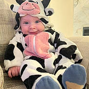 Grayson joined the competition — help win amazing prizes! baby, child, costume, cow_costume, couch, smile, blue_eyes, plush, indoors, cute, infant, apparel, footwear, sitting, happy, portrait, soft, cozy, furniture, baby_clothes