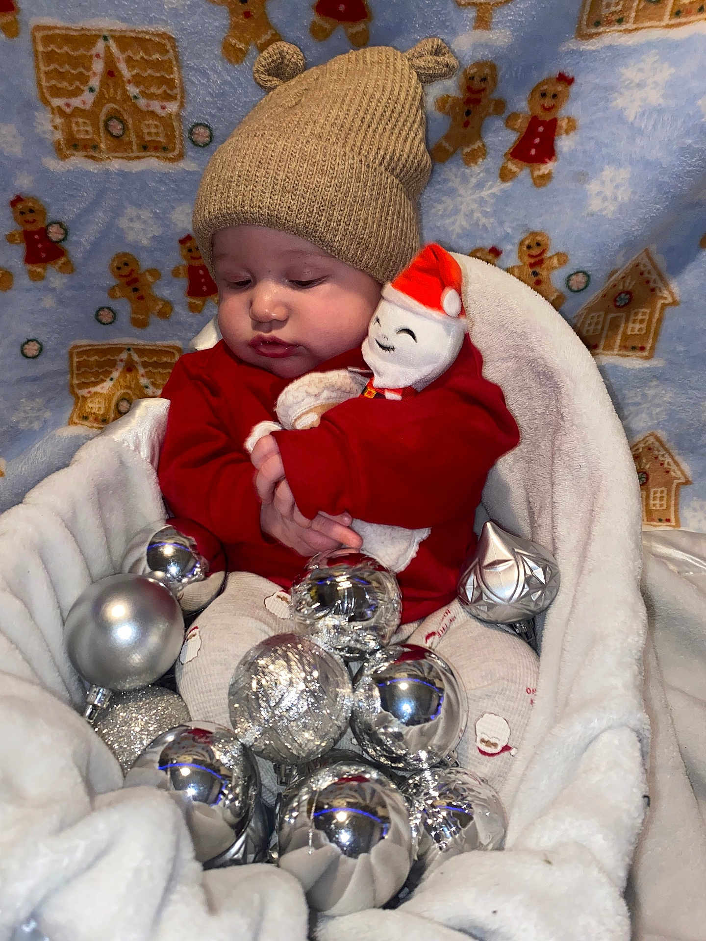 Javonte is registered to the contest to win money with this photo: baby, infant, hat, knitted_hat, plush_toy, santa_toy, christmas_ornaments, silver_balls, blanket, cozy, holiday, festive, gingerbread, pattern, cute, child, soft_fabric, indoor, portrait, smiling_toy