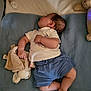 baby, sleeping, blanket, stuffed_animal, soft_toy, teddy_bear, pacifier, crib, infant, blue_shorts, white_shirt, bed, sleep, child, cute, rest, comfort, indoors, cozy, toddler
