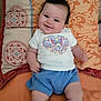 Anabelle Brodin a rejoint le concours — aidez-le/la à gagner de superbes lots ! baby, smiling, child, infant, pillow, patterned_pillow, white_shirt, blue_shorts, butterfly_design, orange_bedding, lying_down, happy, cute, indoors, person, skin, face, head, shorts, toddler