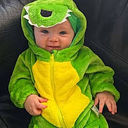 Orsen Rex joined the competition — help win amazing prizes! baby, child, dinosaur_costume, green, yellow, onesie, smile, cute, couch, leather, indoor, infant, hood, teeth, face, hand, seated, plush, zipper, happy