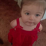 Wednesday is registered to the contest to win money with this photo: baby, barefoot, carpet, casual_clothing, child, curly_hair, cute, expression, face, hair_tie, home, indoor, looking_up, person, portrait, red_dress, small_feet, standing, toddler, young_child