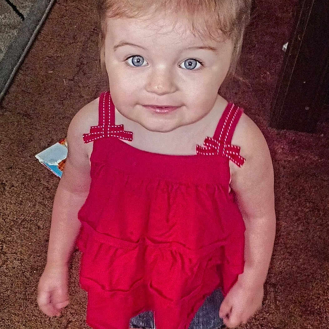 Wednesday is registered to the contest to win money with this photo: baby, barefoot, blue_eyes, brown_hair, carpet, child, cute, facial_expression, fashion, full_body, furniture, indoors, living_room, photography, portrait, red_dress, rug, smiling, standing, toddler