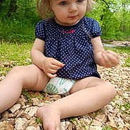 Wednesday joined the competition — help win amazing prizes! baby, barefoot, blonde_hair, child, curious, diaper, eyes, face, forest, greenery, nature, outdoor, pebbles, polka_dot_dress, portrait, rocks, sitting, toddler, trees, woodland