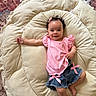 baby, child, girl, smiling, curly_hair, pink_bow, pink_top, denim_shorts, pink_bows, cushion, soft_texture, indoor, rug, patterned_rug, happy, relaxed, laying_down, cute, infant, portrait