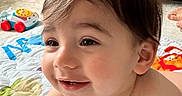 Isaac is registered to the contest to win money with this photo: baby, blanket, child, colorful, couch, cute, face, floor, hair, happy, indoor, infant, living_room, person, play, play_mat, skin, smiling, toddler, toy