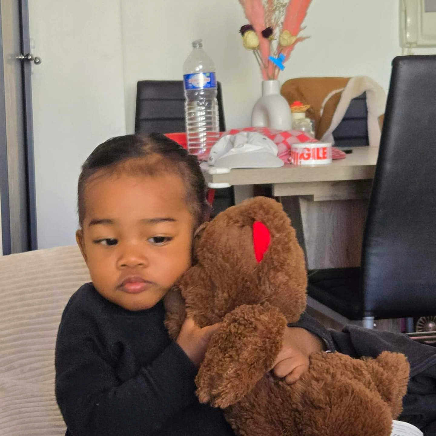 Rabary Anaille participe au concours pour gagner de l'argent avec cette photo : black_sweater, bottle, casual, chair, child, cozy, curly_hair, decor, flower_vase, furniture, home, indoor, jeans, person, seated, table, teddy_bear, thinking, toddler, toy
