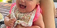 Gabriella joined the competition — help win amazing prizes! baby, smiling, pink_clothing, bib, outdoor, greenery, grass, sunlight, happy, infant, person, skin, arm, hand, leg, sitting, nature, daylight, portrait, cute