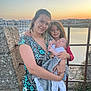 woman, child, baby, family, sunset, waterfront, river, boats, blanket, glasses, smile, embrace, outdoor, fence, stone, nature, clothing, portrait, happy, love