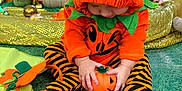 Albie is registered to the contest to win money with this photo: baby, blanket, child, costume, cute, decorations, fall, festive, green, halloween, indoor, orange, people, pink, playing, pumpkin, seated, striped_clothing, toddler, toy