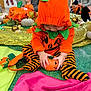 baby, blanket, child, costume, cute, decorations, fall, festive, green, halloween, indoor, orange, people, pink, playing, pumpkin, seated, striped_clothing, toddler, toy