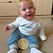 Albie joined the competition — help win amazing prizes! baby, blue_pants, carpet, child, clothing, cute, elephant_drawing, face, floor, happy, indoor, infant, person, sign, sitting, six_months, smiling, sock, white_sweatshirt, wooden_dresser