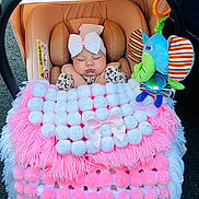 Marlie is registered to the contest to win money with this photo: baby, infant, car_seat, blanket, bow, sleeping, plush_toy, elephant_toy, pink, white, cozy, cute, child, soft, warm, accessory, cute_outfit, seatbelt, comfort, toddler