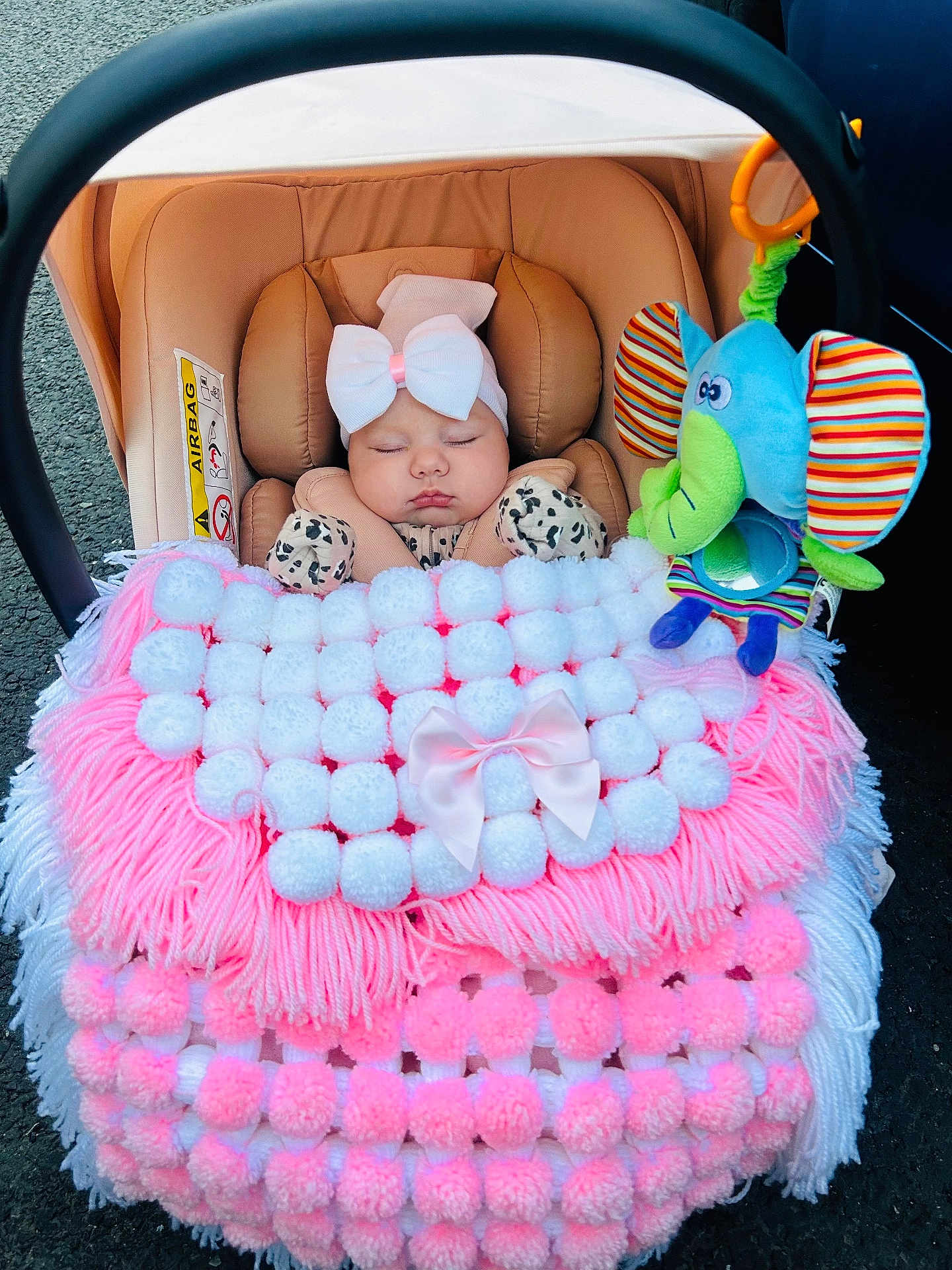 Marlie is registered to the contest to win money with this photo: baby, infant, car_seat, blanket, bow, sleeping, plush_toy, elephant_toy, pink, white, cozy, cute, child, soft, warm, accessory, cute_outfit, seatbelt, comfort, toddler