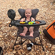 Kruz is registered to the contest to win money with this photo: baby, high_chair, toys, fan, smiling, outdoor, rocks, feet, happy, child, seat, plastic_toys, portable_chair, infant, playtime, summer, sunny, nature, footwear, relaxation