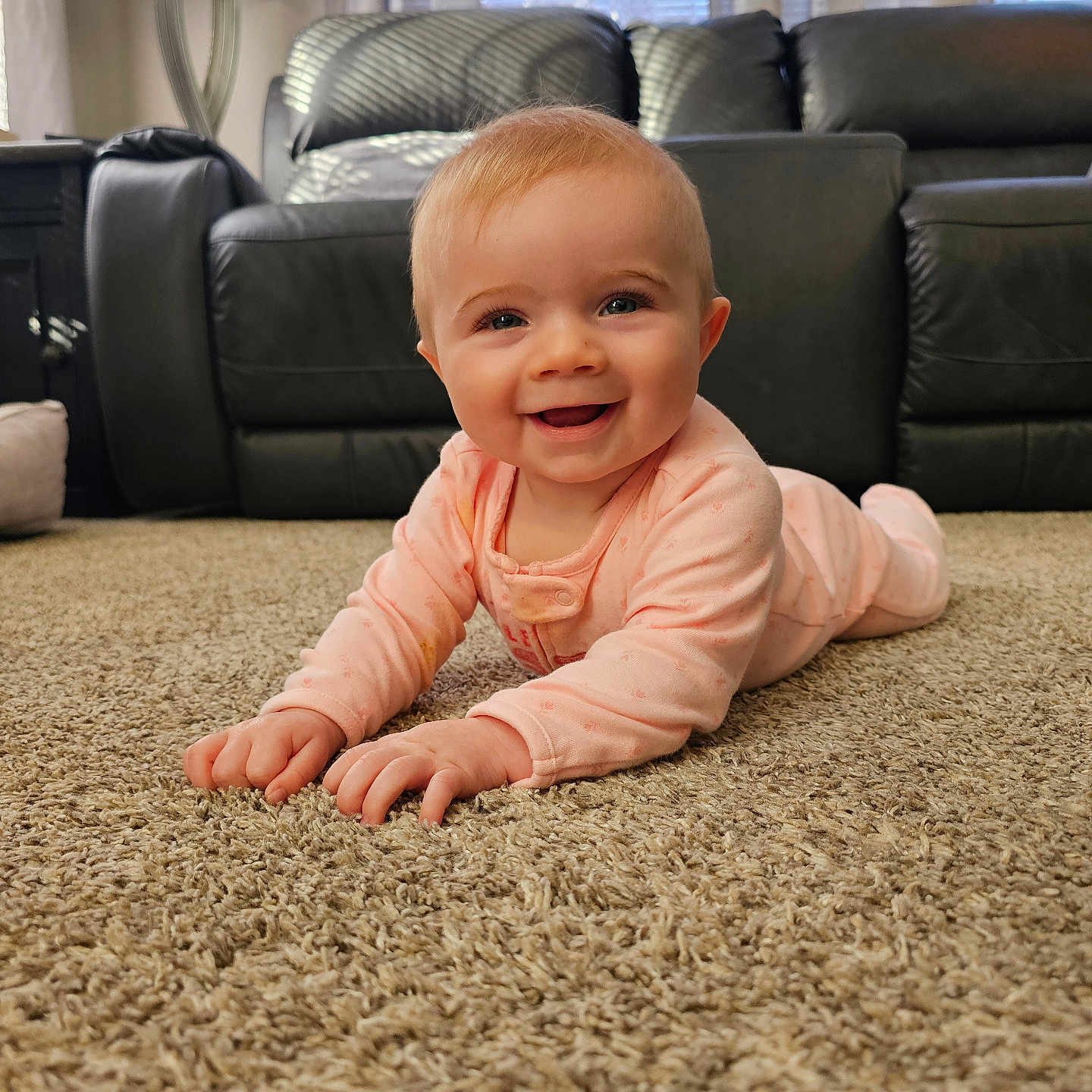 Natalie joined the competition — help win amazing prizes! baby, black_leather, carpet, child, couch, cute, floor, furniture, hands, happy, head, indoor, infant, living_room, natural_light, onesie, person, portrait, smiling, young_child