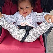 Emy participe au concours pour gagner de l'argent avec cette photo : baby, child, smiling, stroller, happy, playful, white_sweater, floral_leggings, pony_tail, seatbelt, outdoor, person, cute, infant, legs_up, red_stroller, face, clothing, sitting, joyful