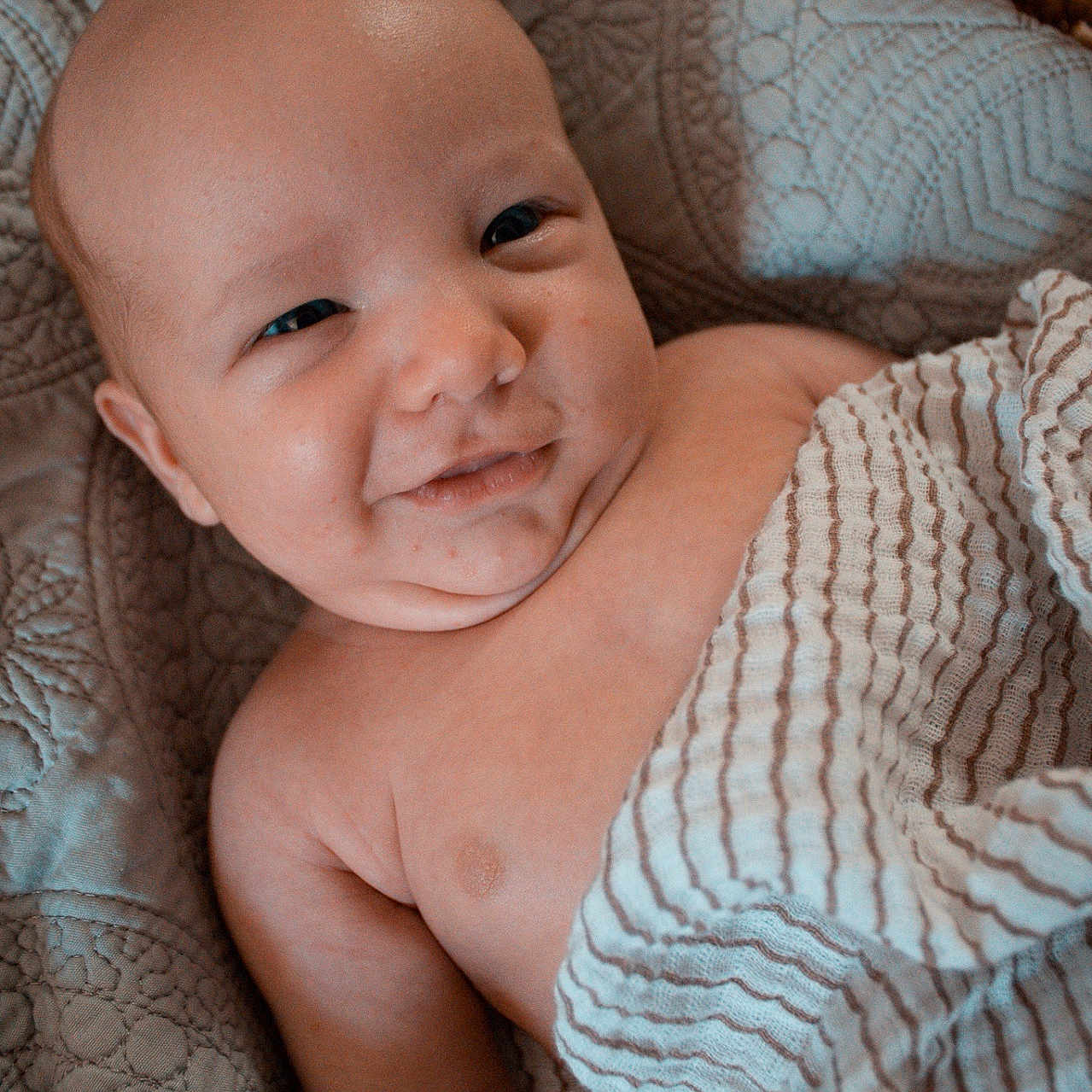 Ezra is registered to the contest to win money with this photo: baby, bed, blanket, bodypart, cradle, face, finger, furniture, hand, happy, head, homedecor, linen, newborn, person, photography, portrait, quilt, smile, towel