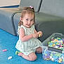 toddler, child, playing, toys, blocks, colorful, floor, blue_floor, plastic_container, gray_couch, indoor, smiling, happy, girl, shorts, sleeveless_top, hair_bow, kneeling, casual_clothing, daylight