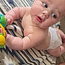 Zane is registered to the contest to win money with this photo: baby, blanket, blue, child, curious, cute, diaper, expression, face, floor, green, hand, indoor, infant, pattern, skin, toddler, toy, white, yellow