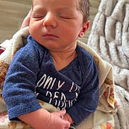 James is registered to the contest to win money with this photo: newborn, baby, sleeping, blanket, blue_onesie, striped_socks, hand, face, closed_eyes, indoor, flooring, cat, orange_cat, cozy, soft_texture, person, infant, resting, cute, home