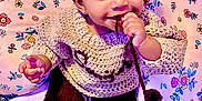 Saniyah is registered to the contest to win money with this photo: baby, bow, child, colorful, cushion, cute, earrings, eyes, face, floral_pattern, hand, headband, indoors, knitted_clothing, person, playful, sitting, smiling, string, toy_phone