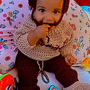 Saniyah joined the competition — help win amazing prizes! baby, bright_colors, child, colorful, cozy, cute, floral_pattern, footwear, hand, happy, hat, indoors, infant, knitted_clothing, pillow, playful, sitting, smiling, toy_phone, young_child