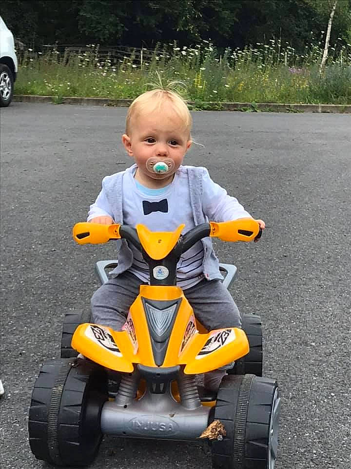 Dylan participe au concours pour gagner de l'argent avec cette photo : asphalt, car, land_vehicle, person, riding_toy, toddler, tricycle, vehicle, wheel