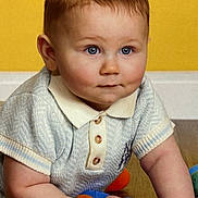 Oaklee is registered to the contest to win money with this photo: baby, child, crawling, blue_eyes, knit_shirt, buttons, toy, colorful, floor, yellow_wall, curious, innocent, indoor, portrait, cute, chubby_cheeks, person, young_child, playful, closeup