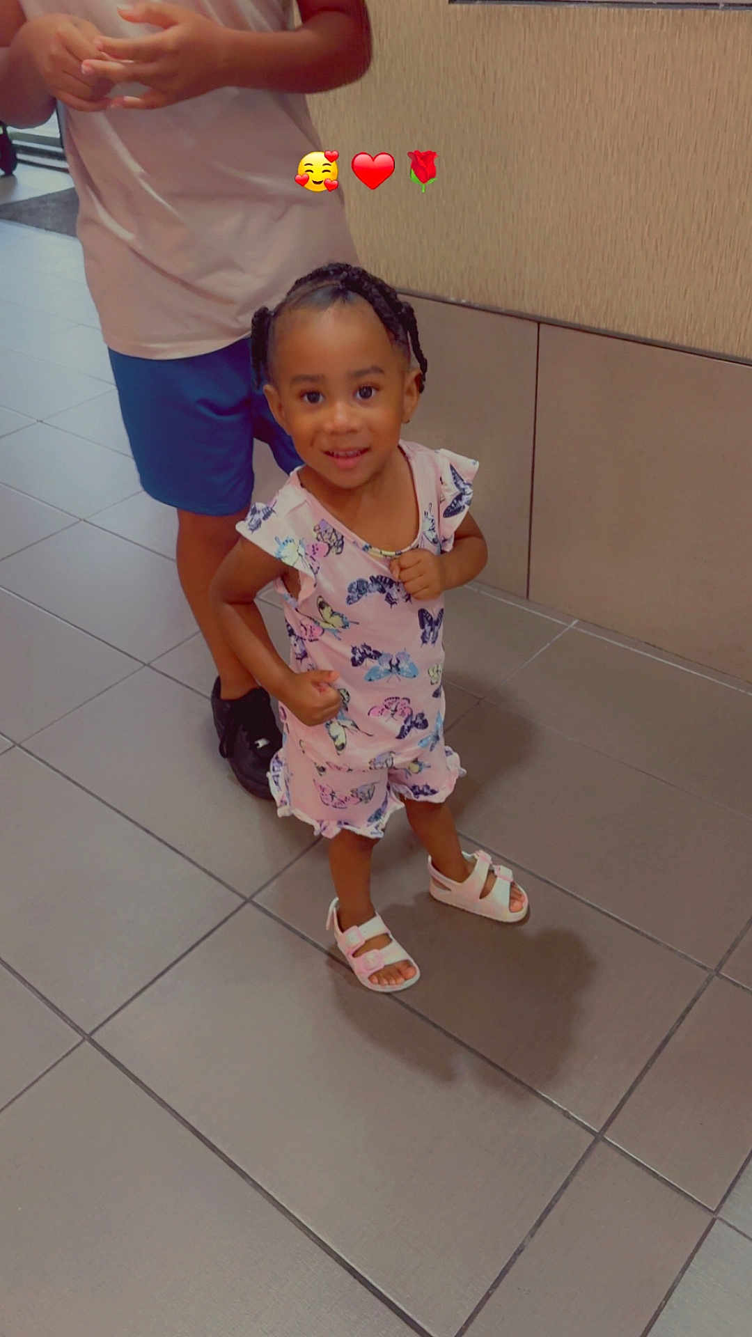 Kaizlynn Mitchell joined the competition — help win amazing prizes! background_wall, braided_hair, butterfly_pattern, casual_clothing, child, feet, floor_tiles, girl, happy, indoor, legs, person, pink_dress, playful, sandals, shadow, smiling, standing, toddler, young_child