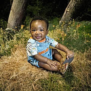 Syncir Williams joined the competition — help win amazing prizes! baby, child, smiling, outdoor, grass, trees, denim_overalls, sandals, nature, cute, happy, sitting, infant, sunlight, greenery, playful, young, portrait, toddler, casual_clothing