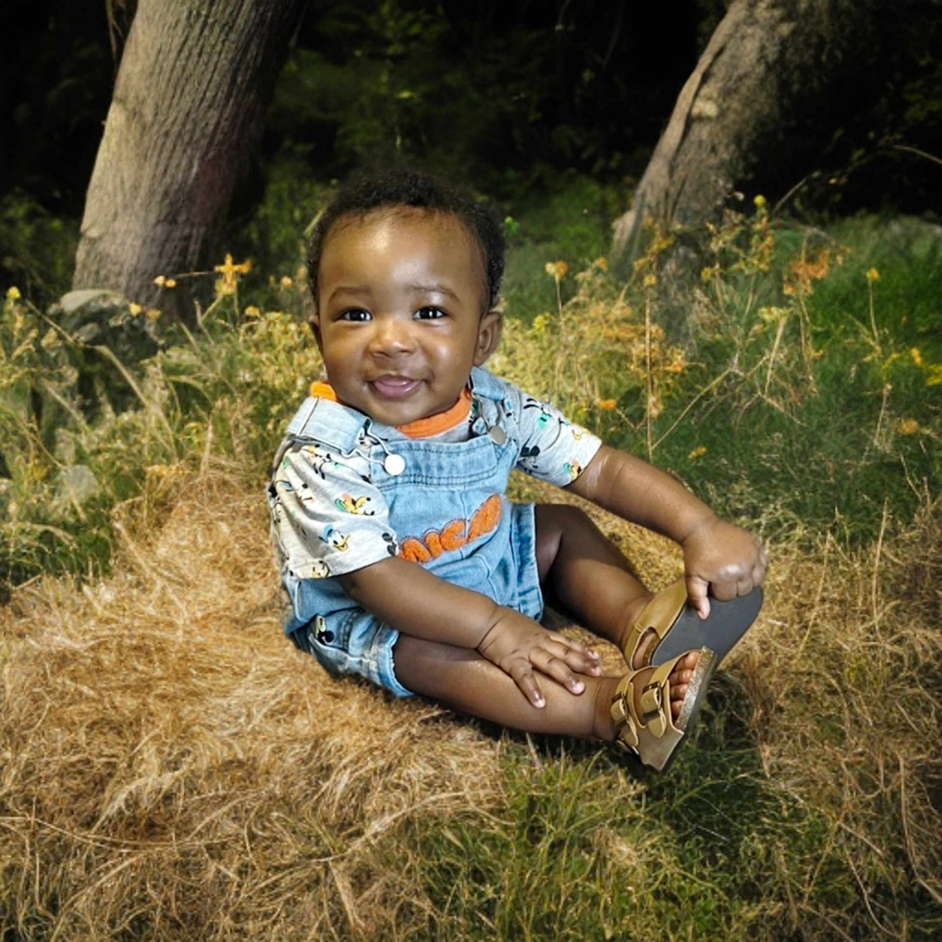 Syncir Williams joined the competition — help win amazing prizes! baby, child, smiling, outdoor, grass, trees, denim_overalls, sandals, nature, cute, happy, sitting, infant, sunlight, greenery, playful, young, portrait, toddler, casual_clothing