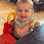 baby, child, high_chair, striped_shirt, blue_eyes, smiling, happy, clapping, sauce_packet, restaurant, table, wooden_table, tile_floor, booth_seating, indoor, person, cute, infant, casual_clothing, seat