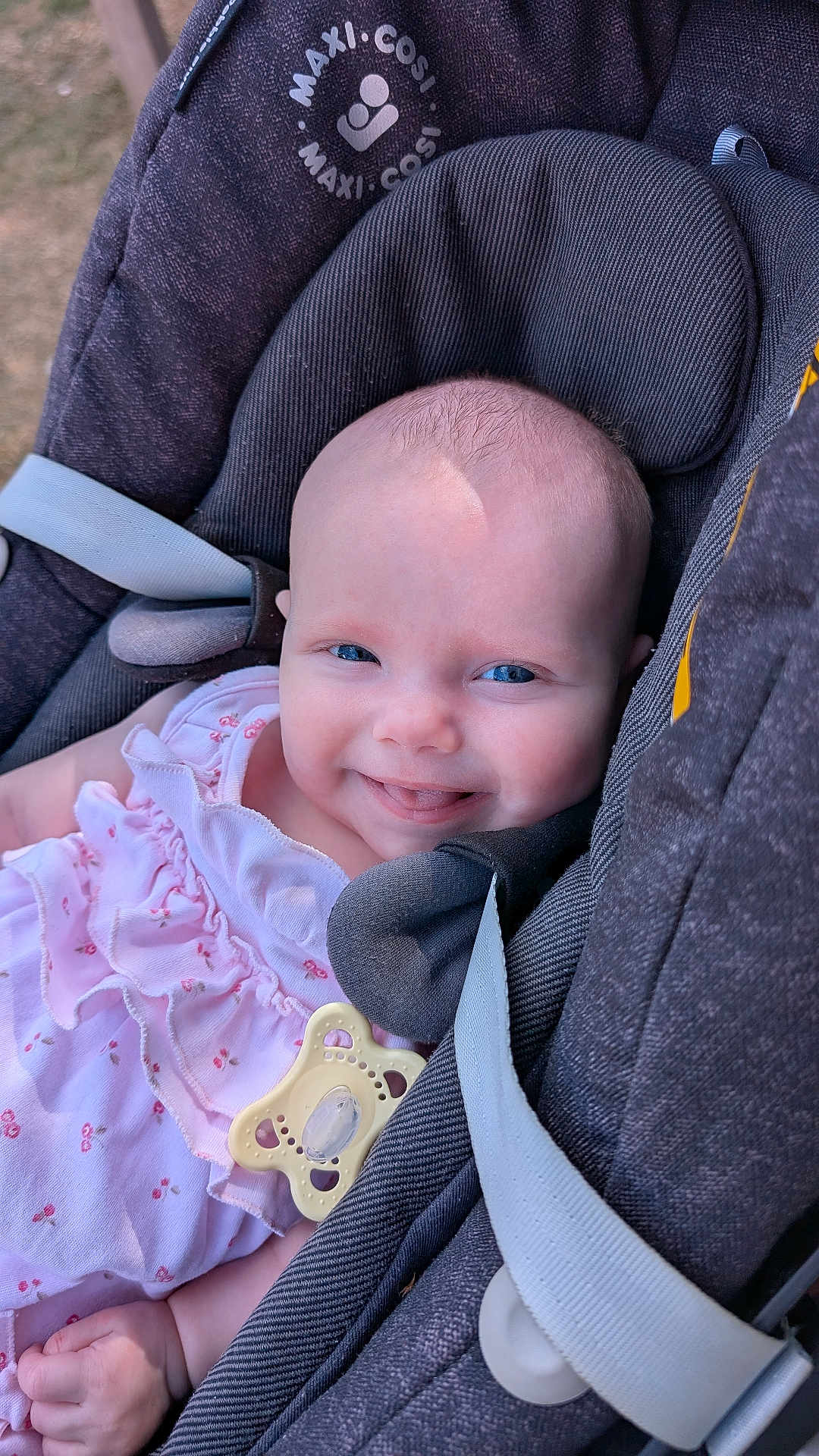 Lily is registered to the contest to win money with this photo: baby, infant, smiling, blue_eyes, pink_dress, pacifier, car_seat, maxi_cosi, child, cute, happy, outdoor, closeup, portrait, seatbelt, clothing, head_support, skin, face, small_hand