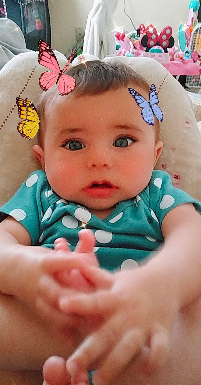 Olivia is registered to the contest to win money with this photo: aqua, arthropod, baby, baby_toddler_clothing, blue, butterfly, cheek, dress, eye, finger, grass, happy, insect, iris, mouth, person, pink, pollinator, skin, sun_hat