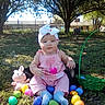 baby, child, pink_outfit, headband, bow, easter_eggs, plush_toy, green_basket, grass, outdoor, tree, dog, sunlight, shade, nature, cute, sitting, toy, holiday, spring