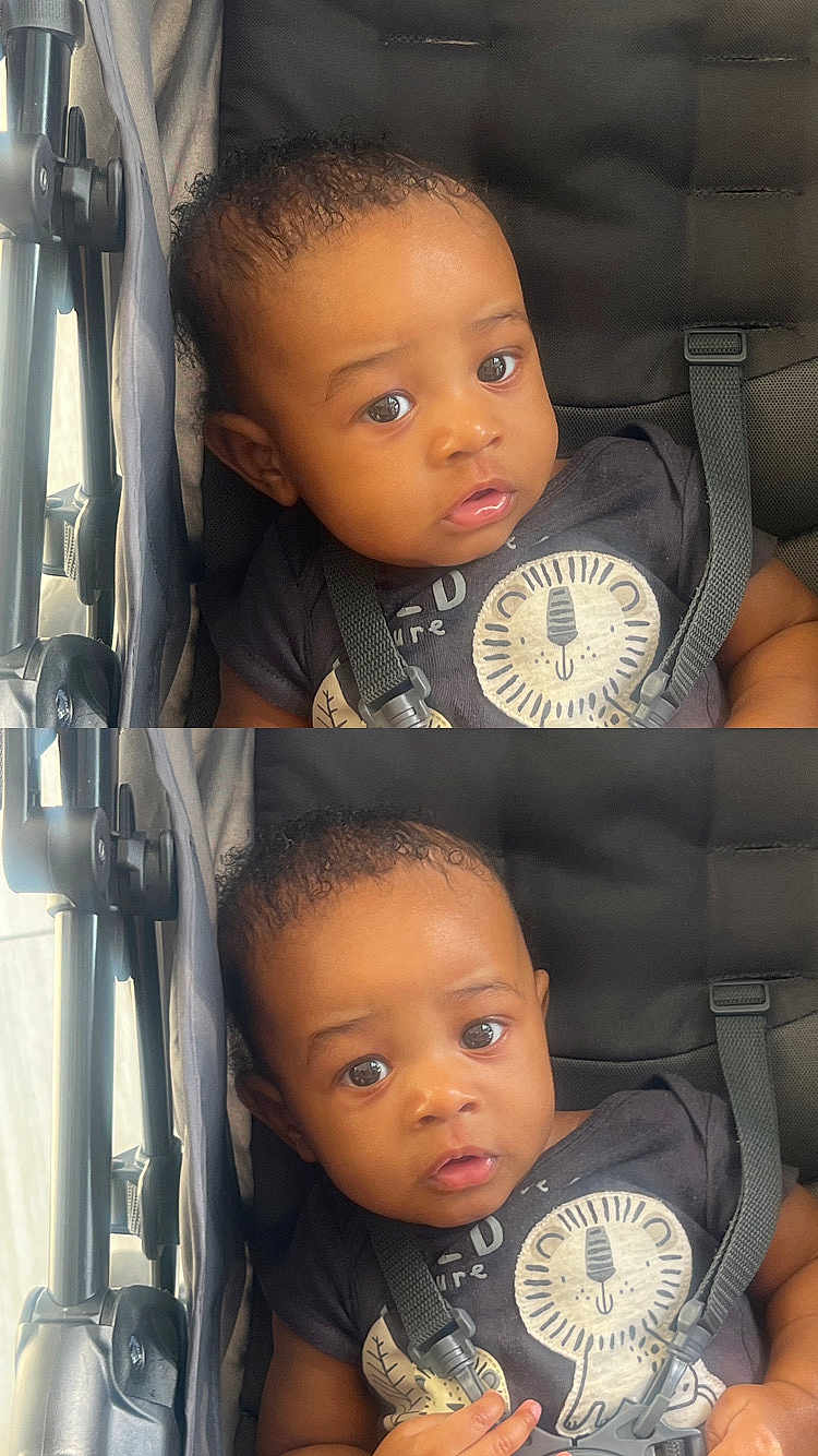Jasiah is registered to the contest to win money with this photo: baby, child, infant, stroller, seatbelt, clothing, lion_print, curly_hair, face, eyes, expression, sitting, black_clothing, straps, indoor, portrait, cute, small_hands, closeup, person