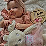 baby, infant, smile, headband, plush_toy, bunny, blanket, milestone_sign, two_months, pink_clothing, soft_texture, cute, child, portrait, lying_down, hand, face, happy, indoors, cozy