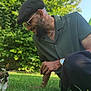 Senua a rejoint le concours — aidez-le/la à gagner de superbes lots ! man, cat, grass, outdoor, greenery, sunlight, smiling, beret, sunglasses, beard, watch, bracelet, necklace, casual_clothing, nature, pet, interaction, crouching, happy, daytime