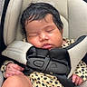 baby, sleeping, car_seat, infant, child, cute, onesie, patterned_clothing, hair, face, closed_eyes, hand, legs, safety_harness, soft_lighting, indoor, portrait, peaceful, young, child_safety